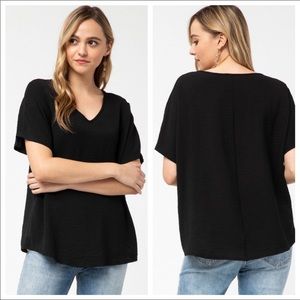 Solid v-neck top featuring rounded hem detail.